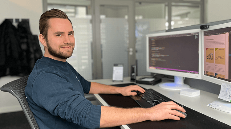 Auszubildender sitzt an seinem Arbeitsplatz und programmiert