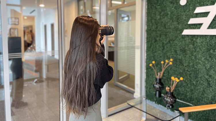 Auszubildende hält eine Kamera vors Gesicht und fotografiert