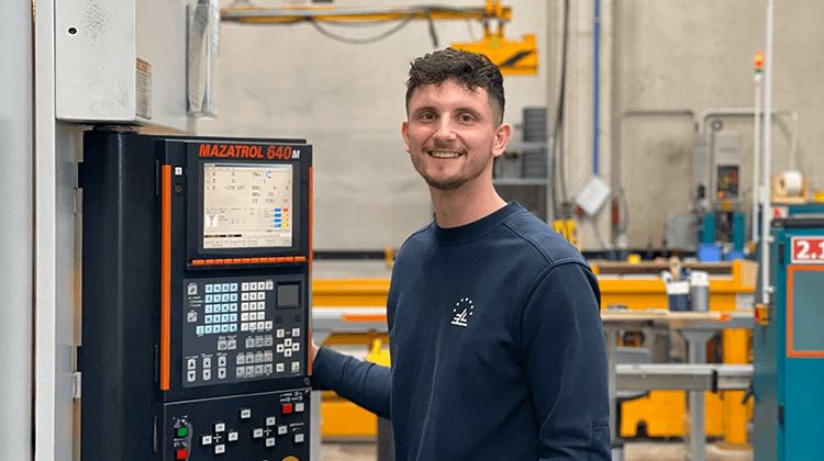 Auszubildender zum Zerspanungsmechaniker steht an der CNC-Maschine